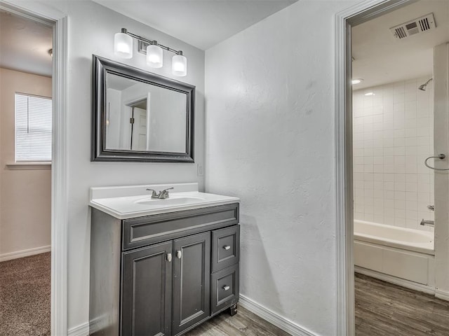 bathroom featuring vanity, hardwood / wood-style flooring, and tiled shower / bath