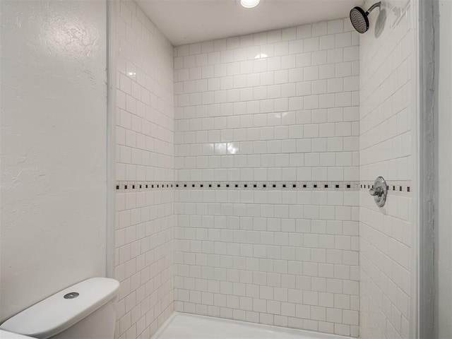 bathroom featuring toilet and a tile shower