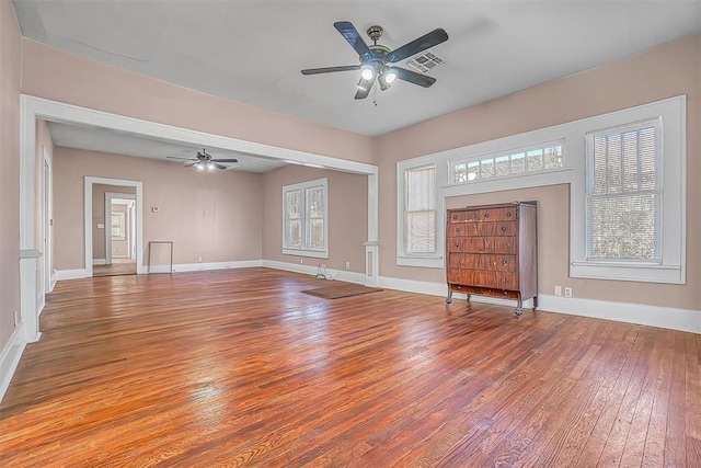 unfurnished living room with a wealth of natural light, ceiling fan, and hardwood / wood-style flooring