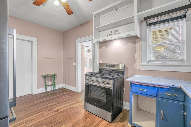 kitchen featuring gas range, light hardwood / wood-style floors, blue cabinets, and ceiling fan