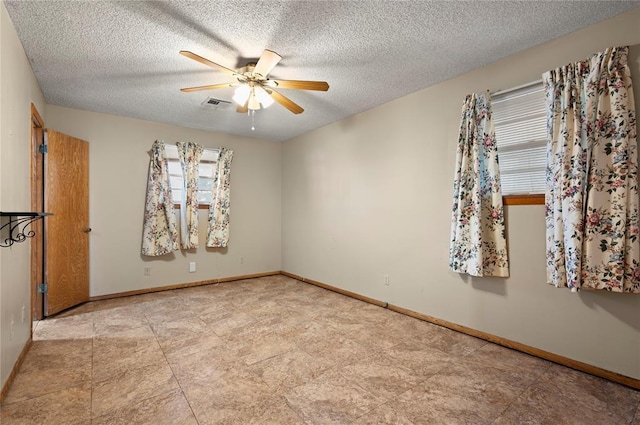 spare room with ceiling fan, plenty of natural light, and a textured ceiling