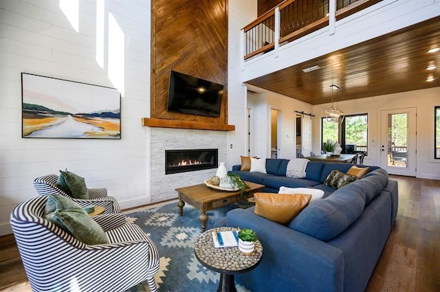 living room with wooden ceiling, a fireplace, a towering ceiling, and hardwood / wood-style floors