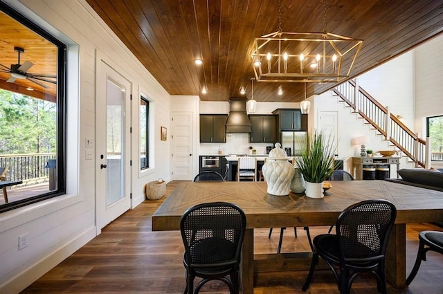 dining area featuring dark hardwood / wood-style flooring, wood ceiling, and ceiling fan with notable chandelier