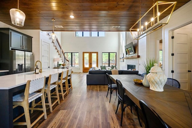 dining area featuring a fireplace, dark wood-type flooring, wooden ceiling, and sink