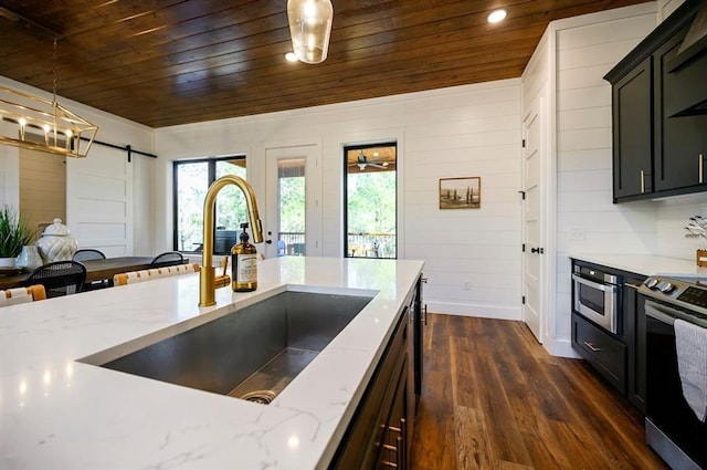 kitchen with a barn door, stainless steel range oven, wood ceiling, and sink