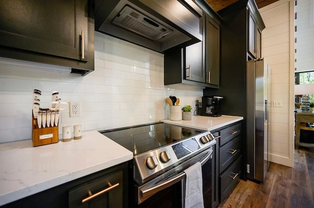 kitchen with decorative backsplash, light stone countertops, wall chimney exhaust hood, electric range, and dark hardwood / wood-style floors