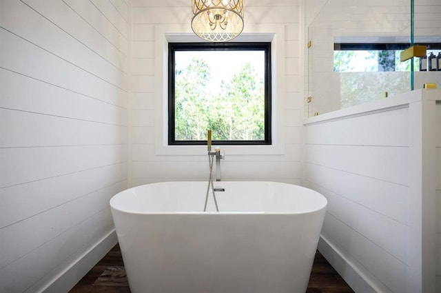 bathroom with a washtub, wood-type flooring, plenty of natural light, and a chandelier