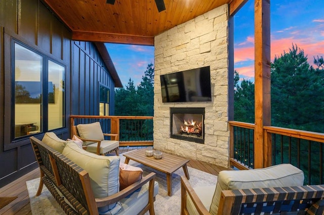 sunroom / solarium with ceiling fan, wood ceiling, and an outdoor stone fireplace