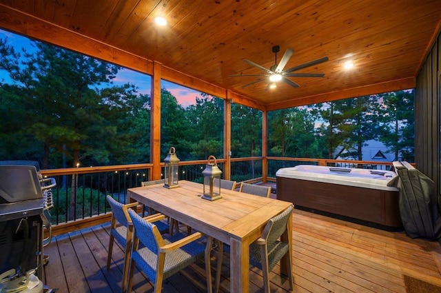 deck at dusk featuring ceiling fan and a hot tub