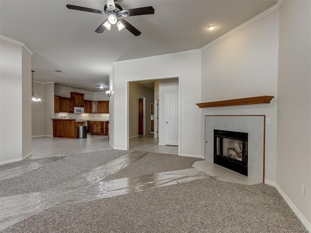 unfurnished living room featuring ceiling fan with notable chandelier, crown molding, light carpet, and a tiled fireplace