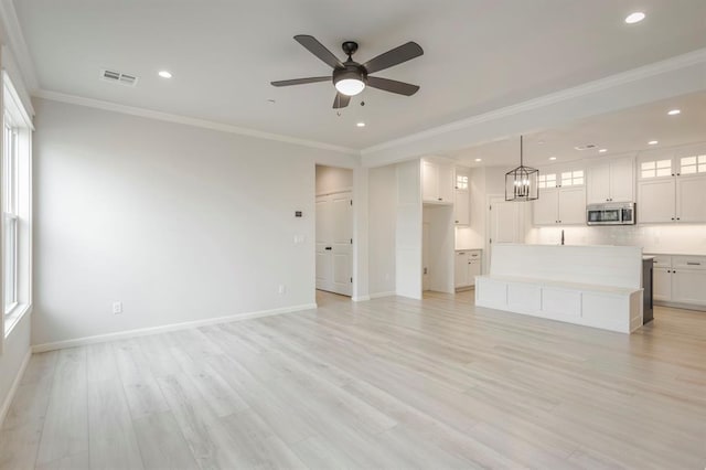 unfurnished living room with ceiling fan with notable chandelier, light hardwood / wood-style floors, and ornamental molding