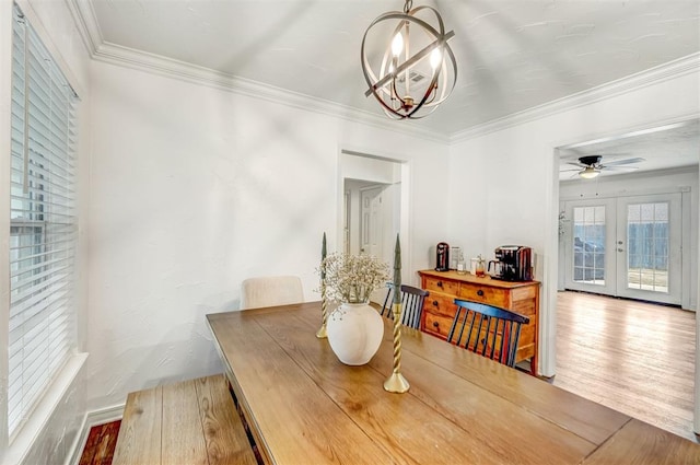 dining room featuring hardwood / wood-style flooring, ceiling fan with notable chandelier, ornamental molding, and french doors