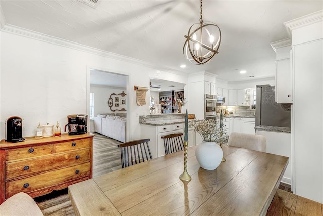 dining space with a chandelier, hardwood / wood-style floors, and ornamental molding