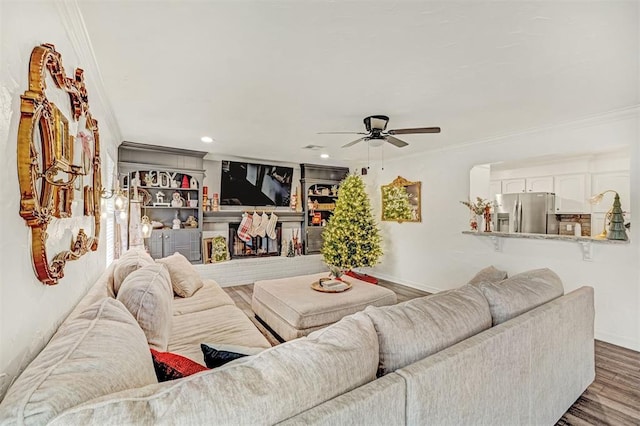 living room with a fireplace, dark hardwood / wood-style flooring, ceiling fan, and crown molding