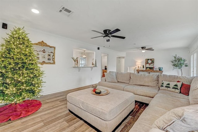 living room with wood-type flooring, ceiling fan, and crown molding