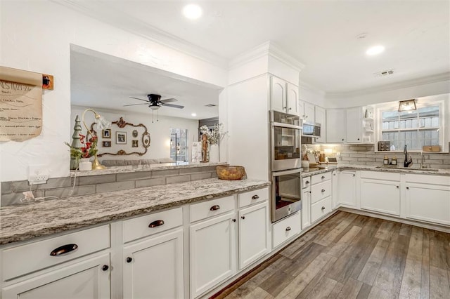 kitchen featuring sink, ceiling fan, appliances with stainless steel finishes, light stone counters, and white cabinetry