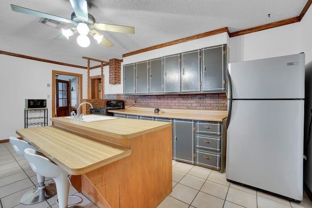 kitchen featuring a breakfast bar, a center island, sink, gray cabinets, and white fridge