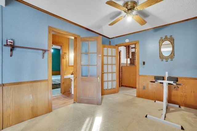 exercise area with french doors, ceiling fan, ornamental molding, and wood walls