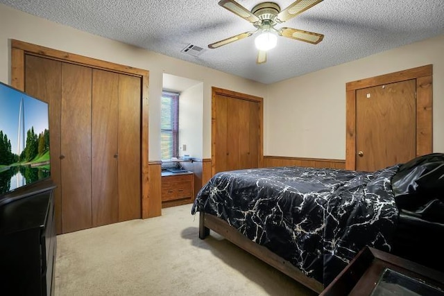 carpeted bedroom featuring ceiling fan, wooden walls, and a textured ceiling