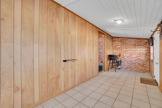 interior space with brick wall, light tile patterned floors, and wooden walls