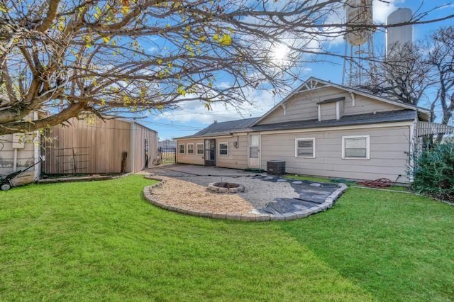 rear view of property featuring a lawn, central air condition unit, a patio area, and an outdoor fire pit