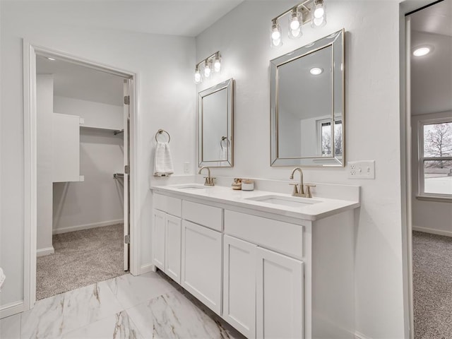 bathroom featuring double vanity, marble finish floor, baseboards, and a sink