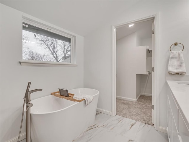 full bathroom with a freestanding tub, baseboards, and marble finish floor