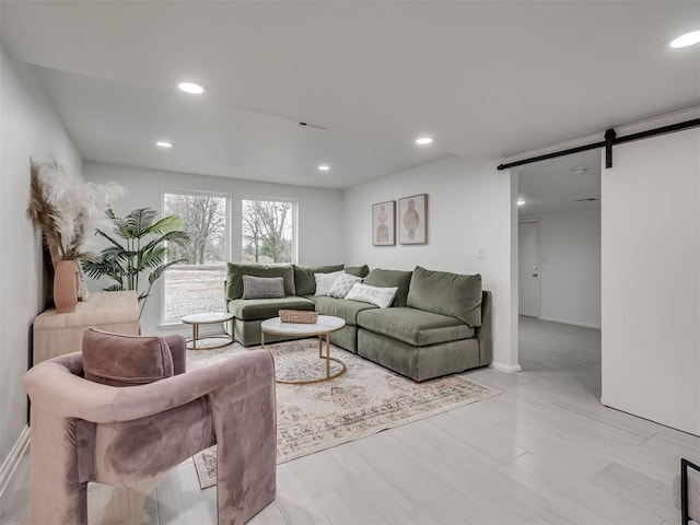 living room featuring baseboards, a barn door, and recessed lighting