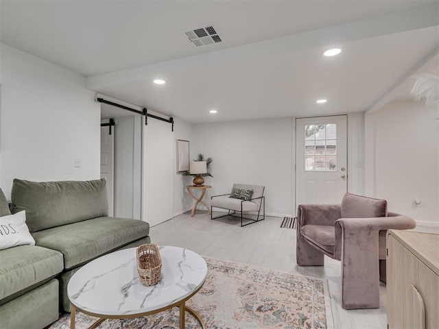 living room with light wood-style floors, a barn door, visible vents, and recessed lighting