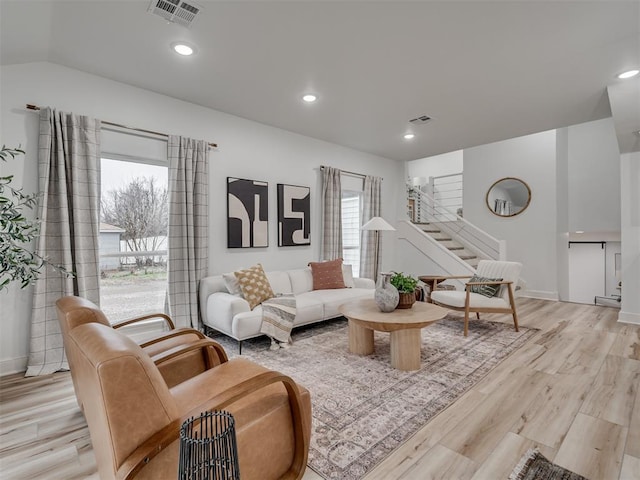 living room with visible vents, light wood-style flooring, stairs, vaulted ceiling, and recessed lighting