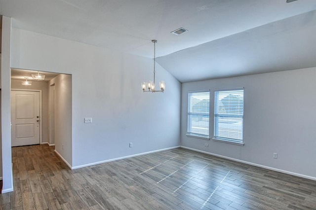 empty room featuring dark hardwood / wood-style flooring, vaulted ceiling, and a chandelier