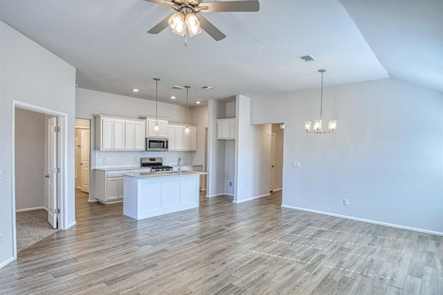 kitchen featuring white cabinetry, appliances with stainless steel finishes, decorative light fixtures, and a kitchen island