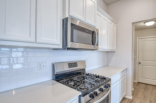 kitchen with stainless steel appliances, light hardwood / wood-style flooring, white cabinets, and decorative backsplash