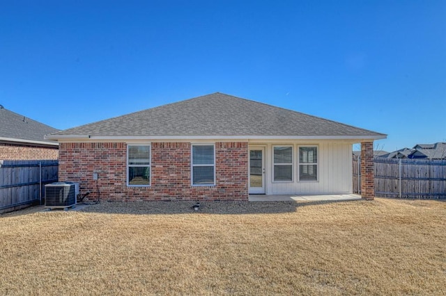 back of house with central AC unit and a lawn