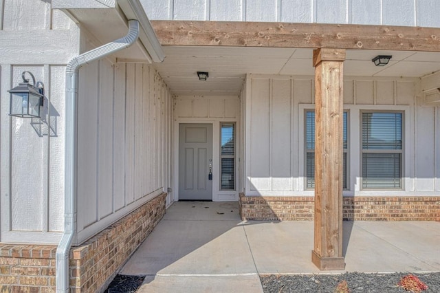 view of exterior entry featuring brick siding and board and batten siding