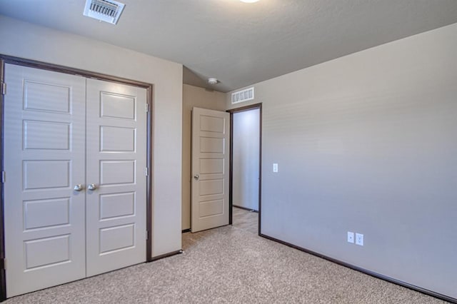 unfurnished bedroom with a closet, visible vents, light carpet, and baseboards