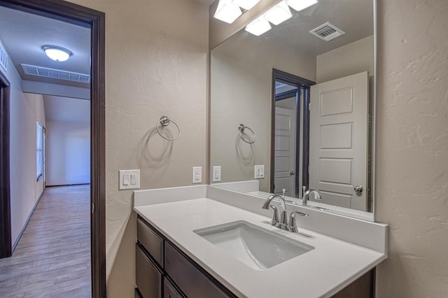 bathroom featuring a textured wall, visible vents, wood finished floors, and vanity