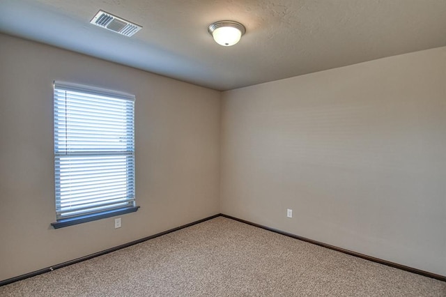 carpeted spare room with visible vents and baseboards