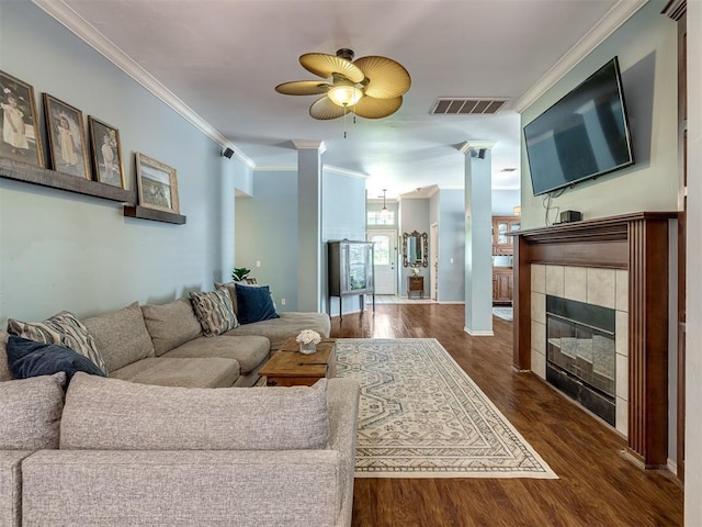 living room featuring crown molding, dark hardwood / wood-style flooring, ceiling fan, and a fireplace