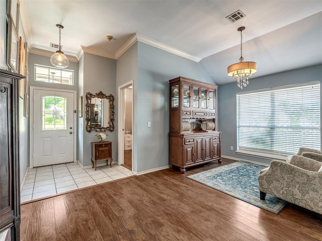 entrance foyer with crown molding, lofted ceiling, an inviting chandelier, and light hardwood / wood-style flooring