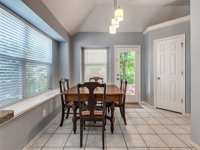 dining space with crown molding, vaulted ceiling, and light tile patterned flooring