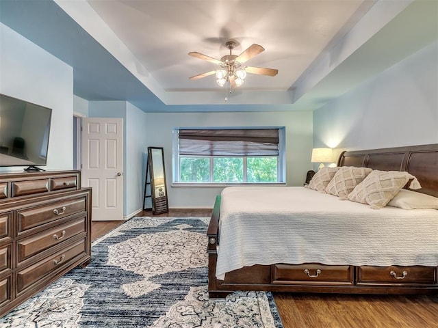 bedroom featuring hardwood / wood-style flooring, a raised ceiling, and ceiling fan