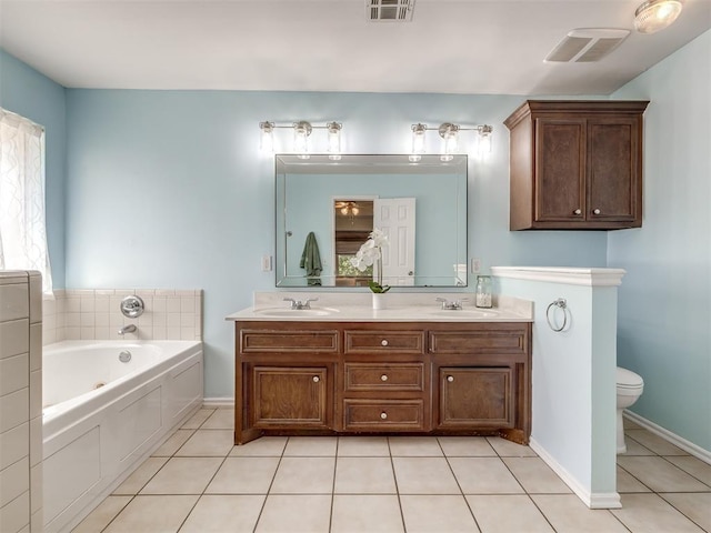 bathroom featuring tile patterned flooring, toilet, vanity, and a tub to relax in