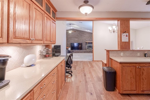 kitchen with decorative backsplash, light hardwood / wood-style flooring, a notable chandelier, hanging light fixtures, and lofted ceiling