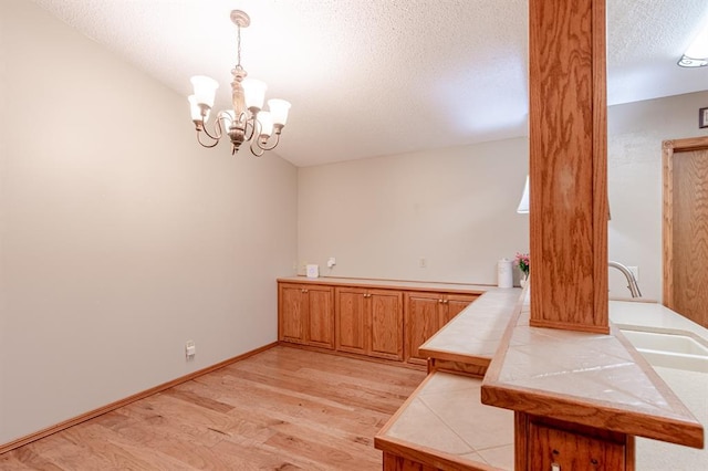 bathroom featuring hardwood / wood-style flooring, a notable chandelier, sink, and a textured ceiling