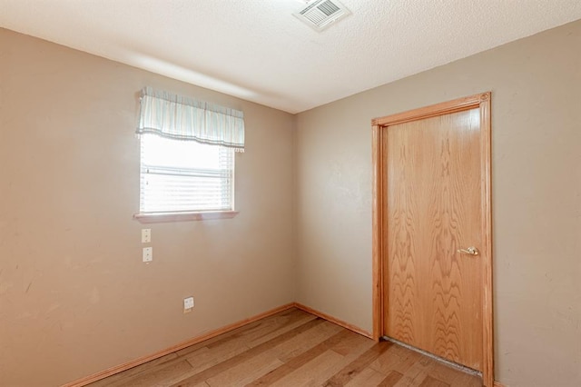 empty room featuring a textured ceiling and light hardwood / wood-style flooring