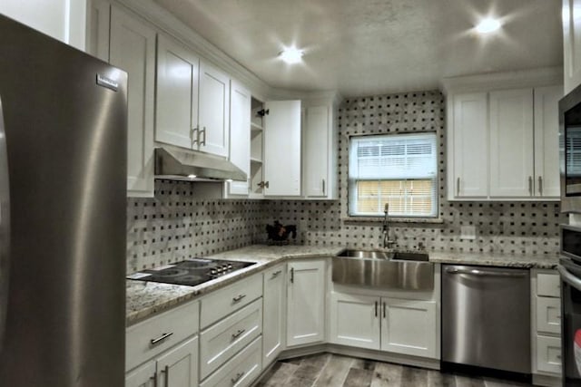 kitchen featuring appliances with stainless steel finishes, tasteful backsplash, light stone countertops, white cabinets, and sink