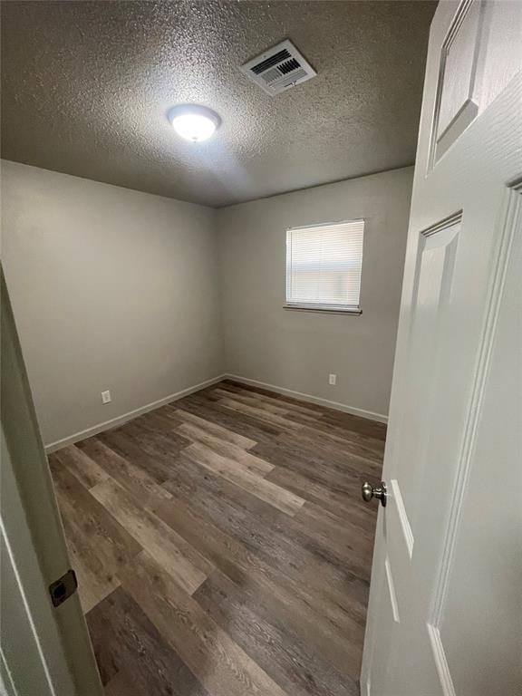 empty room featuring dark hardwood / wood-style flooring and a textured ceiling