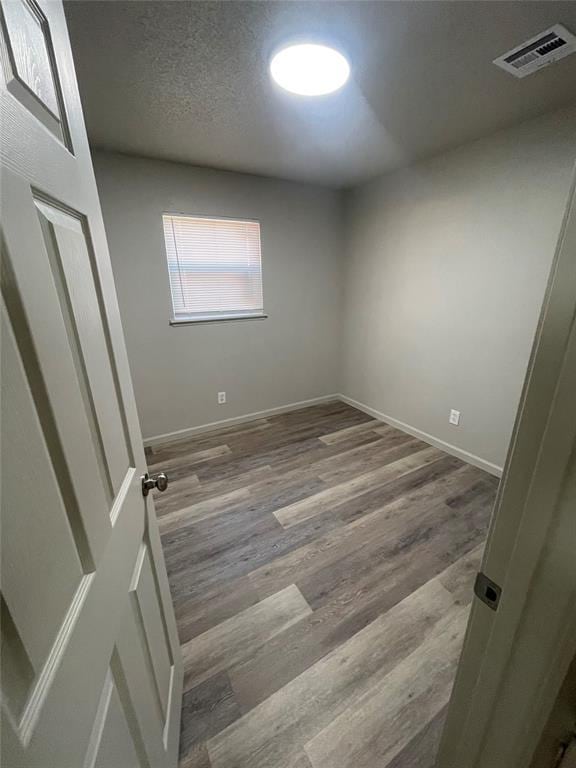 unfurnished room with hardwood / wood-style floors and a textured ceiling