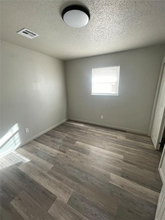 unfurnished room with a textured ceiling and dark wood-type flooring